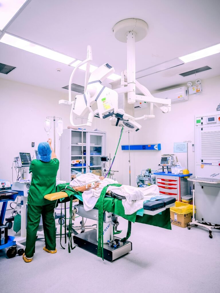 A nurse in a Central Visayas hospital operating room setting adjusting IV equipment during surgery.